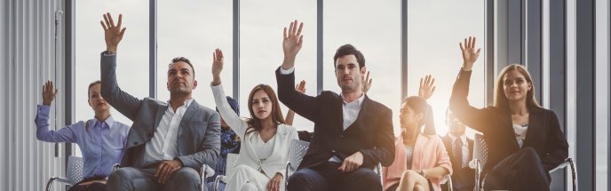 sitting people raising their hands for bidding